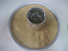 拌匀的蛋糕糊倒入蛋糕模中，抹平蛋糕糊表面。拿起模子在案板上轻磕几下，震出面糊中的
      气泡；