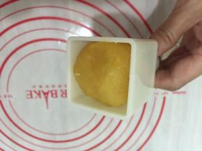 把炒好的绿豆泥分为50克一个。放入模具中，压出来