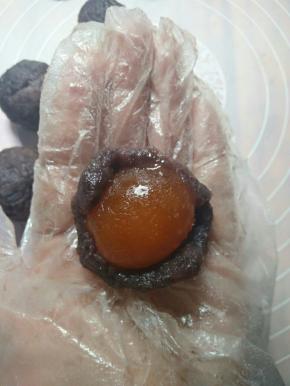 取一份豆沙馅压扁，包入蛋黄，揉圆，每份都依次做好备用。