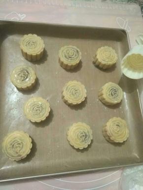 将模具取出，内壁均匀涂抹熟糯米粉，面团放入模具压制成形。