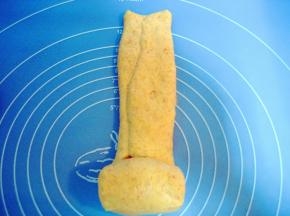 轻轻压下对折好的面片，从下往上卷起；