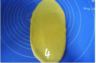 取松驰好的面团压扁，用擀面杖由面团中间向上下两端擀成椭圆形