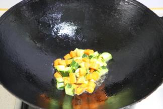 放入胡萝卜和黄瓜丁，翻炒至八分熟盛出