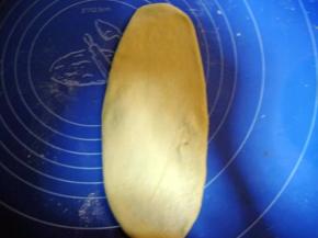 松驰好的面团按扁排气，擀成椭圆形；