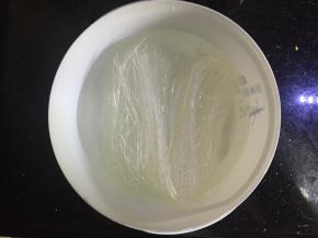 将扇贝一分为二，去掉里面黑色的东西和边上的沙线，清洗干净，将肉取下来，留下带花纹的贝壳，将粉丝放入水里泡软