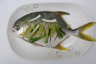 取一个盘子，放上金鲳鱼，表面再放上生姜丝和葱白