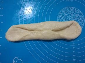 7、	取出其中一个面团，擀成长舌状。两边往中间对折，稍微压扁。