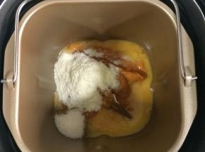 在面包机桶内放入鸡蛋、牛奶南瓜泥，盐和细砂糖要对角放，加入奶粉。