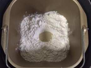 继续加入高筋面粉，在面粉中间挖了洞，把酵母粉放入。启动面包机和面程序，我的面包机一个和面程序是30分钟。