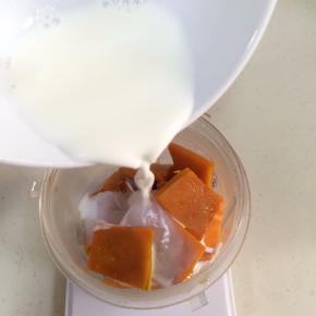 称好熟南瓜片放入料理机杯中，加入牛奶。