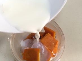 称好熟南瓜片放入料理机杯中，加入牛奶。