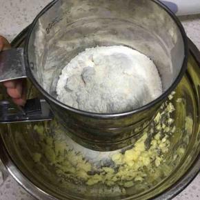 粉类混合物倒入面粉筛中，过筛加入到打发好的黄油中
