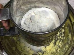 粉类混合物倒入面粉筛中，过筛加入到打发好的黄油中