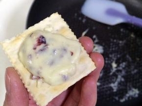 待牛轧糖温热时，右手套上一次性手套取一小团牛轧糖放在苏打饼干上。