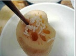 取一大的容器，将处理好的莲藕孔面朝上放置； 泡好糯米控干水份，一点一点将糯米灌进藕孔中。可用筷子辅助来疏通糯米，让米沉到藕底；