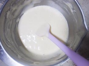 用刮刀隔着淋入温热的牛奶并用蛋抽拌大概30下，最后用刮刀把盆边的蛋糊拌匀