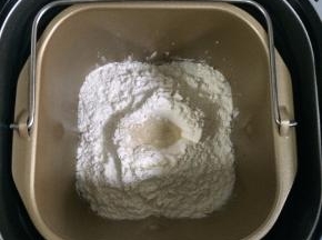 除黄油以外的面团材料都放入面包机内（先液体后粉类的顺序），在面粉中间挖个洞，把酵母粉倒进去，启动和面程序。