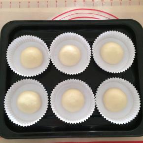 把发好的面团取出排气，分成六等份，把小面团逐个滚圆，放进纸托内。