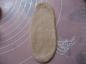 取松驰好的面团，压扁，擀在椭圆形；