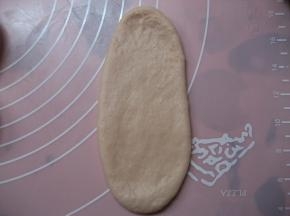 取松驰好的面团，压扁，擀在椭圆形；