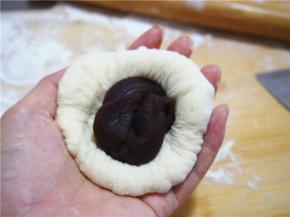 取一块面团擀圆，放入豆沙馅，轻轻收口，捏紧