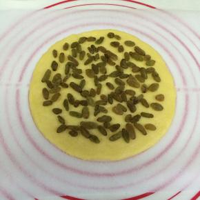 在擀好的饼皮上铺好葡萄干（葡萄干事先温水泡软且沥干水分）。