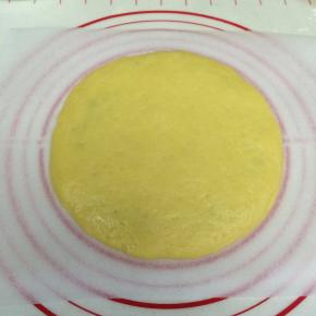 将面团分成两份，放一张油纸，取一份面团在油纸上擀成圆形的饼状。