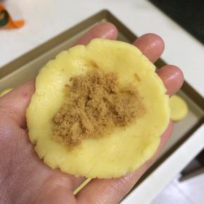 将面团分成16等份的小剂子，取一份搓圆按压平，放上适量的肉松。