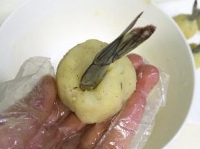 把虾尾插入土豆虾球中，收好边，捏紧了。