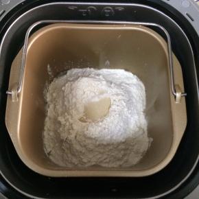 除黄油以外其他食材倒入面包机桶内，按先液体后粉类的顺序，然后在中间挖了洞加入酵母粉。