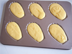 模具上刷一层黄油，将面糊装入裱花袋中，挤入模具