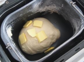 加入牛奶（不要一次加入哦，请根据面团的软硬程度稍作调整），开启揉面程序，揉成光滑面团后加入黄油，继续揉至出膜