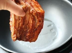 炒锅放油烧热，放入刷好的五花肉，肉皮朝下，开始煎。这一步比较恐怖，会发出啪啪的声音，同时油也会到处溅，所以要盖上锅盖，避免受伤。