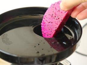 从投料口把火龙果肉投入原汁机。