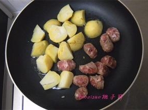 煎锅里倒入食用油，放入土豆块和香肠块小火煎制；
