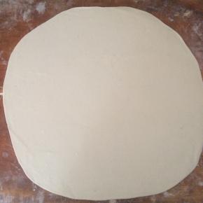 揉匀的面团，用擀面杖擀成大的薄片。