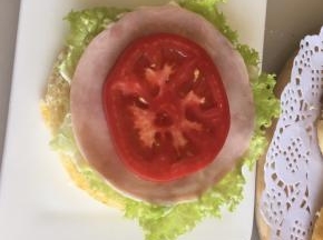 底部面包上放上一片生菜叶，抹上沙拉酱，放一片即食美式火腿片，放上一片番茄