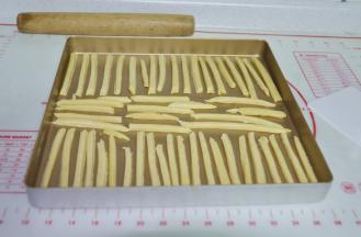 6、用刀把面片切成正方形的长条，摆入烤盘里。