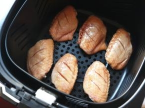 腌好的鸡翅铺在炸锅的炸篮里。