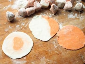 擀成薄薄的饺子皮。中间红色的是用白面团擀片，把红色面团包在里面，另一种就是红色白色面团放一起搓长。都很简单。