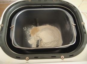 将面粉放入面包机桶中，在角落里放入酵母。