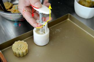 准备一个不粘烤盘，如果没有不站烤盘，可以铺一张锡纸，亚光面向上。去年月饼的实操课上，我发现有的同学不会使用月饼模。这次找了张去年的图给大家示意一下。模具上有两个小耳朵一样的地方，可以卡住我们的手指，整个模具压在烤盘上之后，先整体向下压到按不动。然后拇指向下推的同时，食指和中指向上提。月饼推出大半的时候放松力气自然落下就可以了。千万不要在离烤盘还有段高度的时候就向下推出月饼。不然落下来1容易磕变形 2是不平整