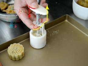 准备一个不粘烤盘，如果没有不站烤盘，可以铺一张锡纸，亚光面向上。去年月饼的实操课上，我发现有的同学不会使用月饼模。这次找了张去年的图给大家示意一下。模具上有两个小耳朵一样的地方，可以卡住我们的手指，整个模具压在烤盘上之后，先整体向下压到按不动。然后拇指向下推的同时，食指和中指向上提。月饼推出大半的时候放松力气自然落下就可以了。千万不要在离烤盘还有段高度的时候就向下推出月饼。不然落下来1容易磕变形 2是不平整