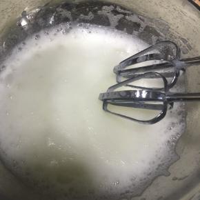 打发至泡沫细腻时再加入1/3的细砂糖，继续打发