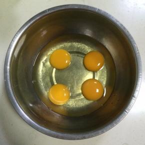 在打蛋盆内打入4个鸡蛋。