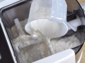 将面粉倒入面条机里。