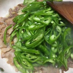 炒至肉片微微变色，下入青椒不停翻炒。