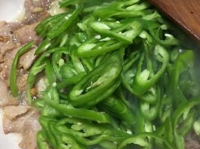 炒至肉片微微变色，下入青椒不停翻炒。