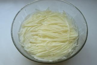 两个土豆去皮，用刨丝器刨成细丝，浸入水中洗净淀粉。