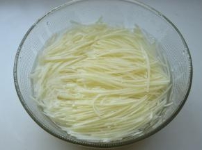 两个土豆去皮，用刨丝器刨成细丝，浸入水中洗净淀粉。